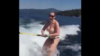 Topless girl rides on the water skiing