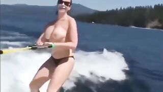 Topless girl rides on the water skiing