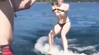 Topless girl rides on the water skiing