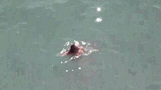 A pair of naked people enjoy each other in the sea